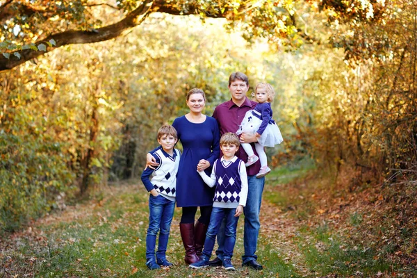 Porträtt av unga föräldrar med tre barn. Mor, far, två barn bröder pojkar och liten söt småbarn syster flicka har roligt tillsammans i höstskogen. Lycklig familj på fem — Stockfoto