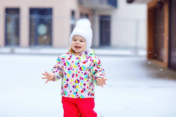 Портрет маленькой девочки, гуляющей на улице зимой. Милый малыш ест сладкие конфеты с леденцами. Ребенок веселится в холодный снежный день. Ношение теплый ребенок красочные одежды и шляпы с качелями. — стоковое фото