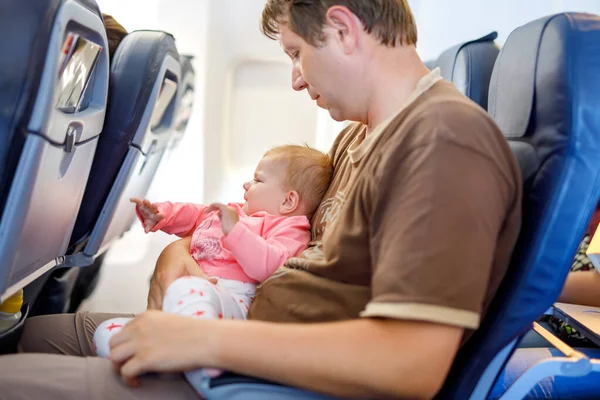 Nuori väsynyt isä ja hänen itkevä tytär lennon aikana lähdössä lomalle — kuvapankkivalokuva