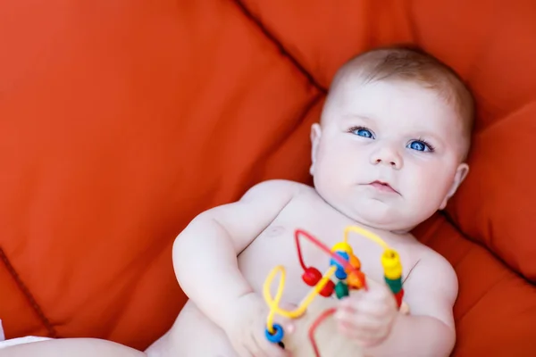 Entzückendes neugeborenes Baby spielt mit buntem hölzernem Rasselspielzeug — Stockfoto