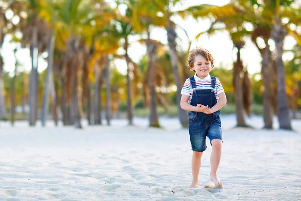 Adorable petit garçon actif qui s'amuse sur la plage de Miami, Key Biscayne. Joyeux enfant mignon relaxant, jouant avec le sable et profitant d'une journée chaude ensoleillée près des paumes et de l'océan — Photo