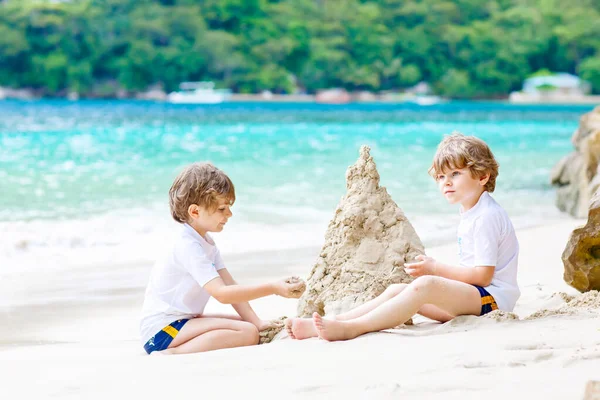 Twee jongen jongens bouwen van zandkasteel op tropisch strand — Stockfoto