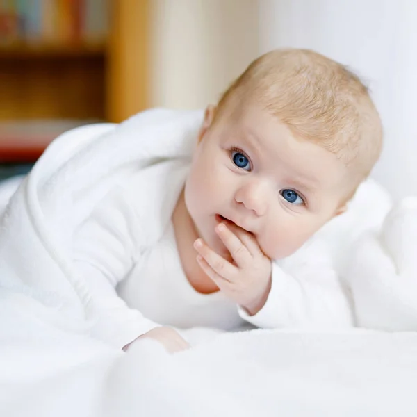 Niña con ojos azules que usa toalla blanca o manta en un dormitorio blanco y soleado. Niño recién nacido relajándose en la cama. Guardería para niños. Textil y ropa de cama para niños. Feliz linda niña recién nacida o niño . —  Fotos de Stock