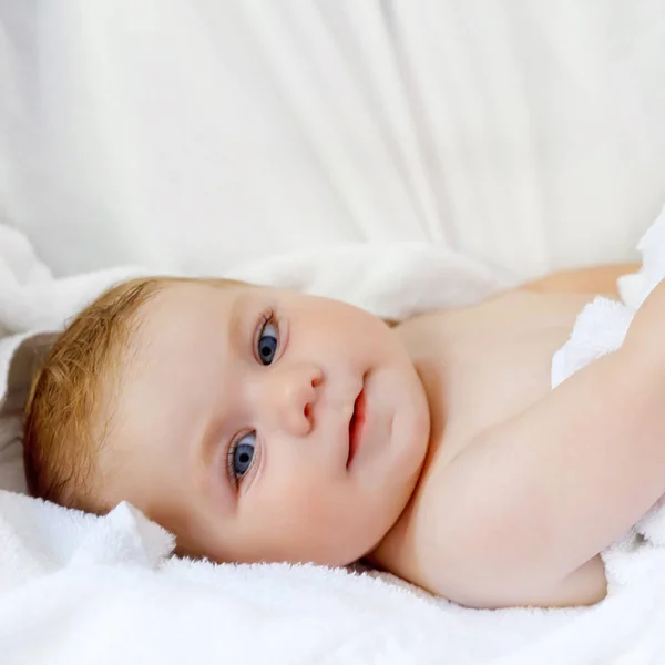 Cute little baby playing with own feet after taking bath. Adorable beautiful girl wrapped in white towels. Happy healthy baby — Stock Photo, Image