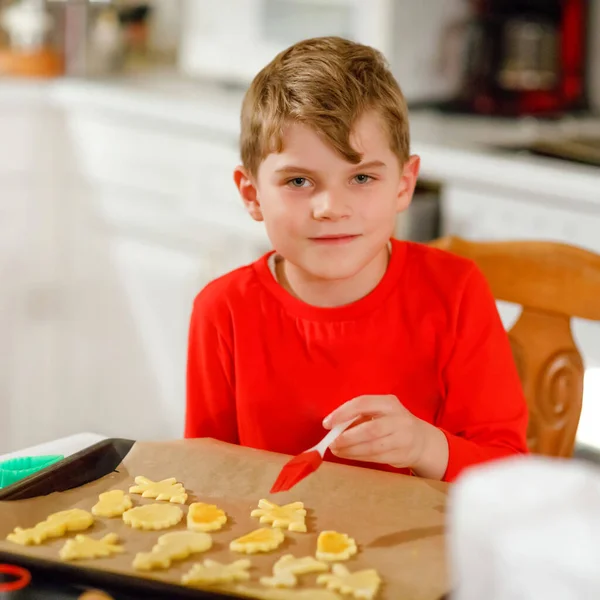 Netter kleiner Junge, der zu Hause Lebkuchen backt. entzückendes blondes Kind, das Spaß in der heimischen Küche hat. Traditionelle Freizeit mit Kindern an Weihnachten. — Stockfoto