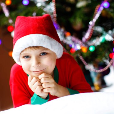 Noel Baba şapkası Noel ağacı ve arka plan ışığı ile küçük çocuk çocuk. Garland ve renkli aydınlatma ile. Mutlu okul öncesi çocuk kutluyor xmas, Aile tatil. Çocuk kıyafeti.