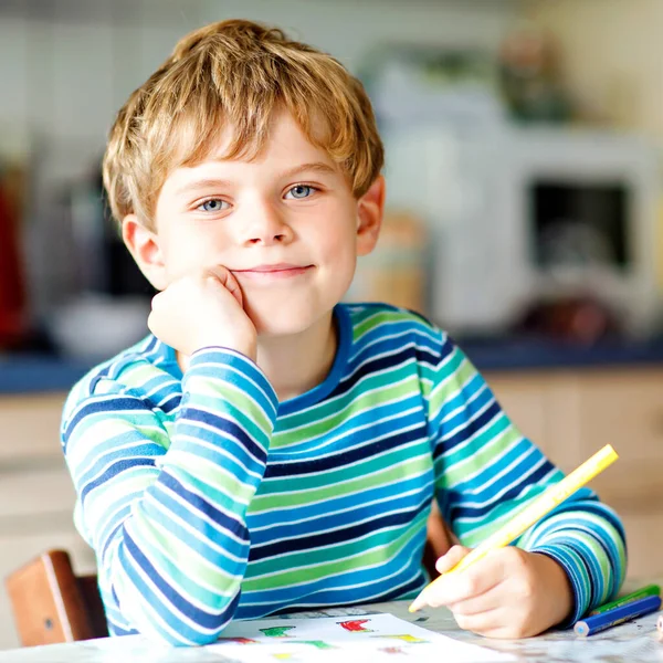 Retrato de menino menino bonito escola feliz saudável em casa fazendo lição de casa. Criança escrevendo com lápis coloridos, dentro de casa. Escola primária e educação. Criança aprendendo a escrever letras e números — Fotografia de Stock