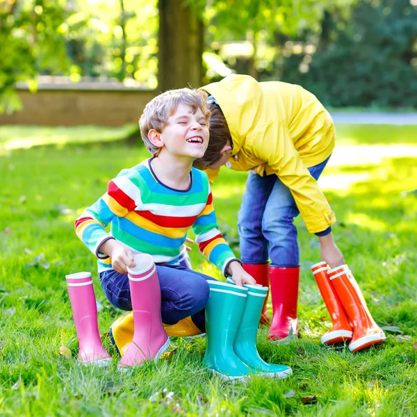 Dwójka małych chłopców, urocze rodzeństwo z dużą ilością kolorowych butów przeciwdeszczowych. Dzieci w różnych gumowych butach i kurtkach. Obuwie na deszczowy upadek. Zdrowe bliźniaki i najlepsi przyjaciele bawiący się na świeżym powietrzu — Zdjęcie stockowe