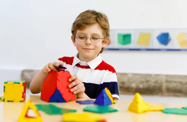 Ragazzo felice con gli occhiali divertirsi con la costruzione e la creazione di figure geometriche, imparare la matematica e la geometria — Foto Stock