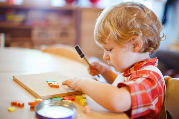 小可爱的幼儿玩木制拼图锤玩具。 在幼稚园或幼稚园玩耍的快乐幼儿。 从事日托活动的儿童 — 图库照片