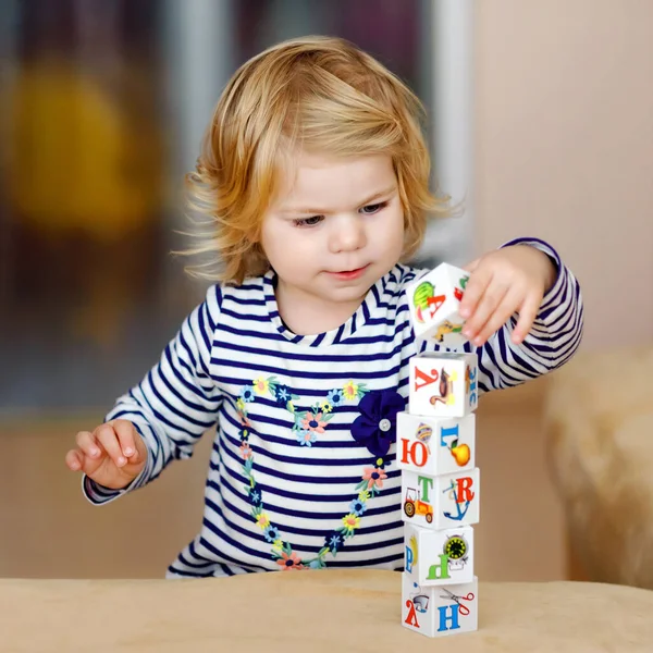 Menina adorável criança brincando com brinquedos educativos no berçário. Criança saudável feliz se divertindo com blocos de plástico diferentes coloridos em casa. Bonito bebê aprendizagem criação e construção — Fotografia de Stock