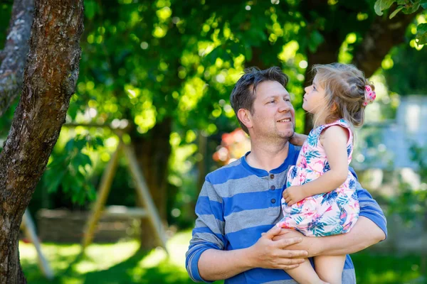 Gelukkige jonge vader heeft plezier leuke peuter dochter, familie portret samen. man met mooi meisje in de zomertuin. Vader met klein kind buiten, knuffelend. Liefde, hechting. — Stockfoto