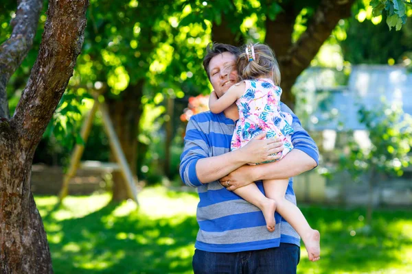 Ευτυχισμένος νεαρός πατέρας διασκεδάζει χαριτωμένο κοριτσάκι κόρη, οικογενειακό πορτρέτο μαζί. άντρας με όμορφο κοριτσάκι στον καλοκαιρινό κήπο. Ο μπαμπάς με το μικρό παιδί έξω, αγκαλιασμένοι. Αγάπη, δέσιμο.. — Φωτογραφία Αρχείου