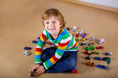 Hoş sarışın çocuk içeride bir sürü oyuncak arabayla oynuyor. Sağlıklı çocuk salgın koronavirüs karantina hastalığı sırasında eğleniyor. Evde yalnız çocuk, kapalı kreş..