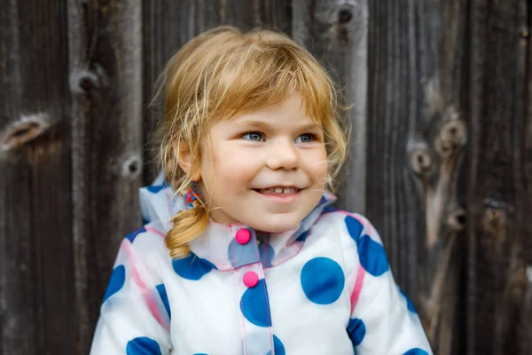 Retrato al aire libre de la pequeña niña sonriente feliz con chaqueta de lluvia en el día nublado lluvioso. Lindo niño sano en ropa colorida actividad al aire libre —  Fotos de Stock