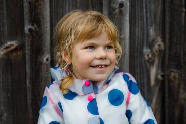 Portrait en plein air d'une heureuse petite fille souriante portant une veste de pluie le jour nuageux pluvieux. Enfant sain mignon en vêtements colorés activité de plein air — Photo