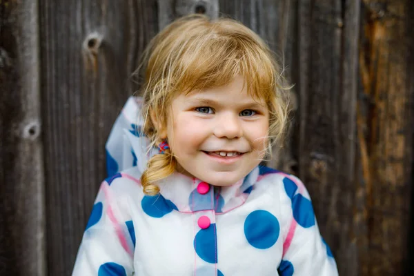 Retrato al aire libre de la pequeña niña sonriente feliz con chaqueta de lluvia en el día nublado lluvioso. Lindo niño sano en ropa colorida actividad al aire libre —  Fotos de Stock