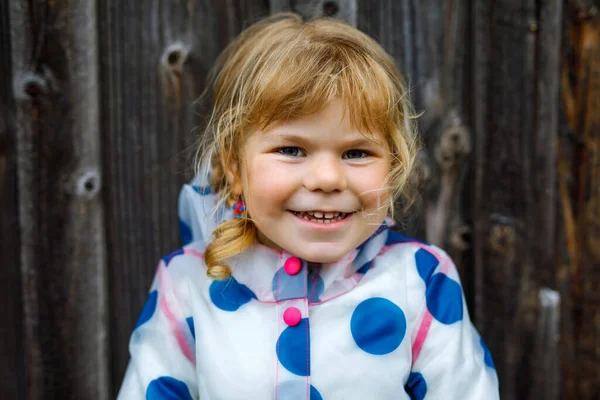 Retrato al aire libre de la pequeña niña sonriente feliz con chaqueta de lluvia en el día nublado lluvioso. Lindo niño sano en ropa colorida actividad al aire libre — Foto de Stock