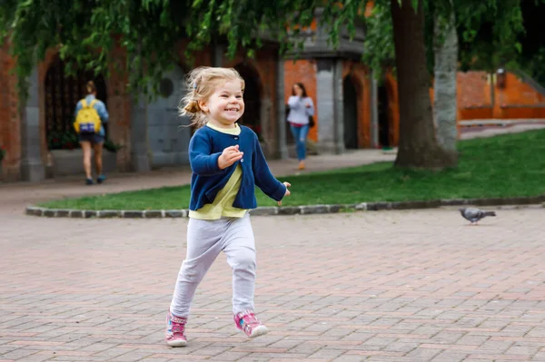 Linda menina criança pequena feliz correndo no parque em Dublin, Irlanda. Sorrindo e rindo bebê criança se divertindo passando férias em família na natureza. Viajar com crianças pequenas — Fotografia de Stock