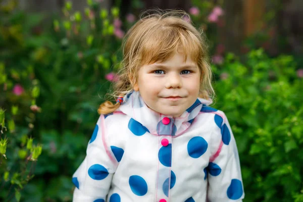 Outdoor portret van vrolijk lachend peutermeisje in regenjas op regenachtige bewolkte dag. Schattig gezond kind in kleurrijke kleding outdoor activiteit — Stockfoto