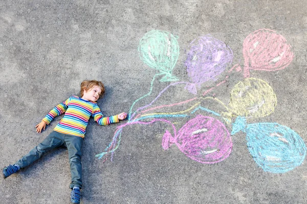 Niño divirtiéndose con globos de colores dibujando con tiza —  Fotos de Stock