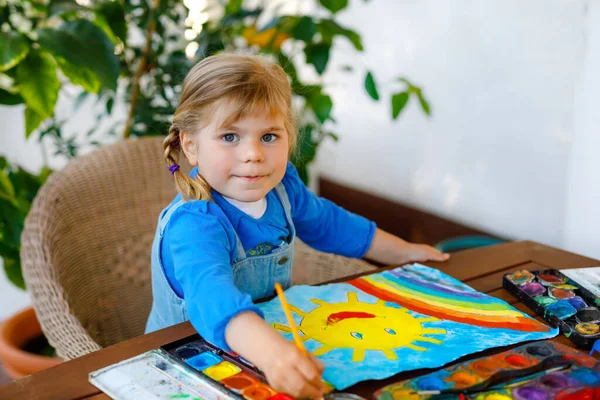 대유행 코로나 바이러스 격리 질병 기간 동안 무지개와 태양을 물의 색으로칠 하는 어린 소녀. 아이들은 라떼라는 단어로 무지개를 그리며 전 세계를 돌아다닙니다. 행복 한 아이 — 스톡 사진