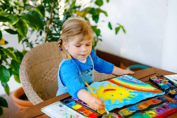 幼児の少女が虹と太陽を水の色で描くパンデミックコロナウイルスの隔離病の間に。子供たちは言葉で世界中の虹を描くすべてがうまくいくことができます。幸せな子供 — ストック写真