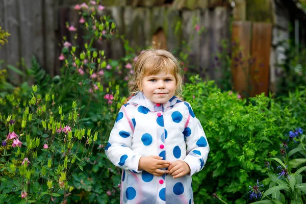 Outdoor portret van vrolijk lachend peutermeisje in regenjas op regenachtige bewolkte dag. Schattig gezond kind in kleurrijke kleding outdoor activiteit — Stockfoto