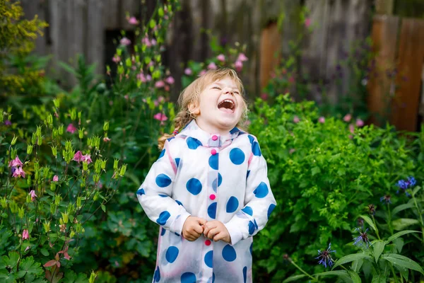 Outdoor portrait of happy smiling little toddler girl wearing rain jacket on rainy cloudy day. Cute healthy child in colorful clothes outdoor activity — Stock Photo, Image