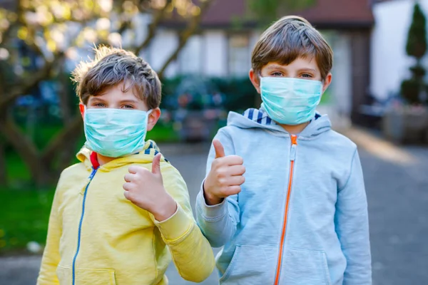 Двоє дітей у медичній масці захищаються від пандемії коронавірусної хвороби. Діти, милі брати і сестри і найкращі друзі використовують захисне обладнання як боротьбу проти ковадла 19 . — стокове фото