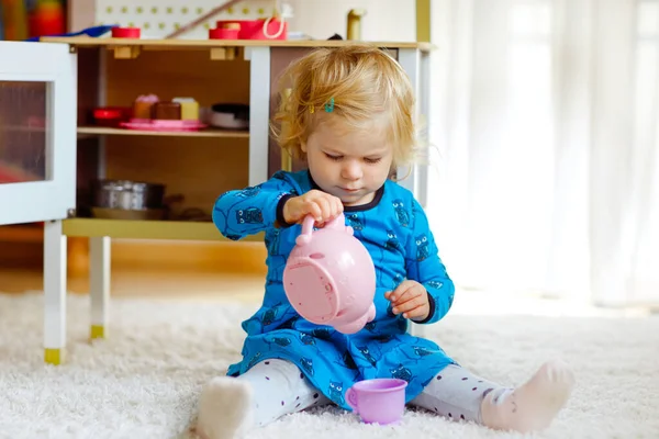 Adorable linda niña pequeña jugando con la cocina de juguete Feliz niño sano divirtiéndose con el juego de rol, jugando con la tetera de vajilla en casa o en el vivero. Hija activa con juguete. —  Fotos de Stock