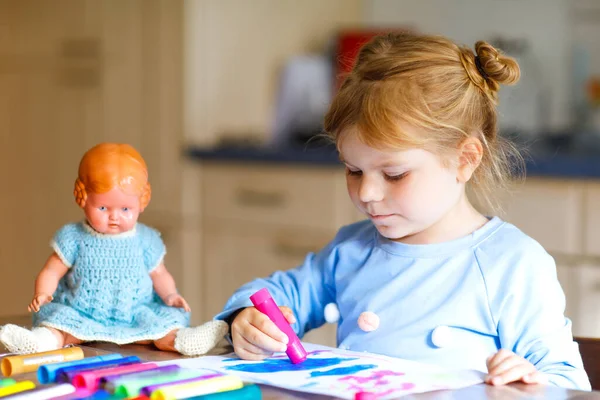 Little alone toddler girl painting with felt pens during pandemic coronavirus quarantine disease. Happy creative child with old vintage doll, homeschooling and home daycare with parents — Stock Photo, Image