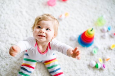 Evde ya da çocuk odasında eğitici oyuncaklarla oynayan sevimli, güzel bir kız bebek. Mutlu sağlıklı çocuk renkli ahşap çocuk oyuncak piramidiyle eğleniyor. Çocuk farklı yetenekler öğreniyor.