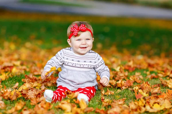 Schattig klein meisje in het najaar park op zonnige warme oktober dag met eiken en esdoorn blad. Val gebladerte. Familie buitenpret in de herfst. kind glimlachend. — Stockfoto