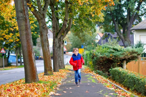 Menino feliz correndo na rua outonal depois da escola. Miúdo feliz com as férias escolares. Criança com roupas de moda outono vestindo óculos de olho — Fotografia de Stock
