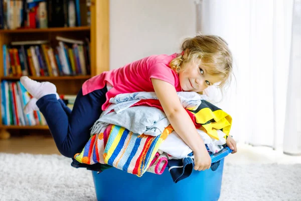 Egy kislány egy nagy kosár tiszta szennyessel, vasalásra készen. Boldog gyönyörű kisbaba és kislánya segít anyának a házimunkában és a ruhákban. — Stock Fotó