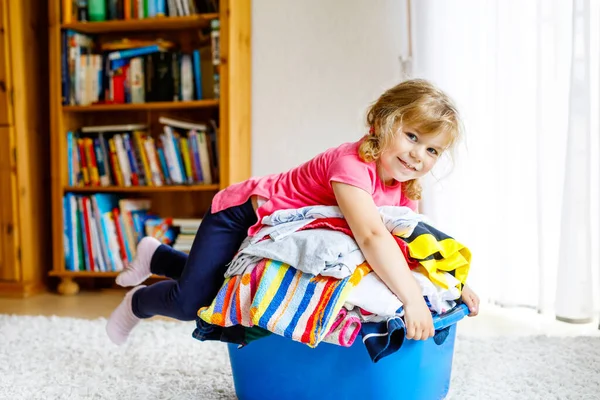 Niña con una gran cesta de ropa limpia y fresca lista para planchar. Feliz hermoso niño y bebé hija ayudando a la madre con las tareas domésticas y la ropa. — Foto de Stock