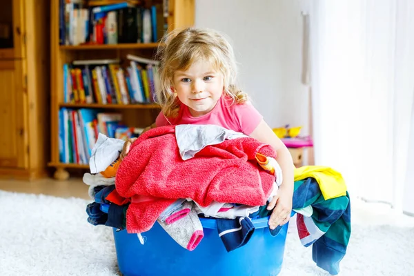 Niña con una gran cesta de ropa limpia y fresca lista para planchar. Feliz hermoso niño y bebé hija ayudando a la madre con las tareas domésticas y la ropa. — Foto de Stock