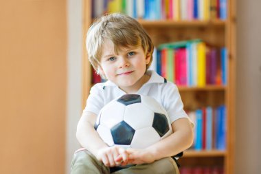 Futbol topu olan sarışın anaokulu çocuğu TV 'de futbol maçı izliyor. Komik, mutlu, ağlayan çocuk hayranı eğleniyor ve futbol takımını destekliyor. Şampiyonlar ve Dünya Kupası konsepti