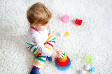 Evde ya da çocuk odasında eğitici oyuncaklarla oynayan sevimli, güzel bir kız bebek. Mutlu sağlıklı çocuk renkli ahşap çocuk oyuncak piramidiyle eğleniyor. Çocuk farklı yetenekler öğreniyor.