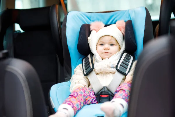 En söt liten flicka med blå ögon som sitter i bilsätet. Leksaksbarn i vinterkläder åker på familjesemester och jorney. Säker resa, barnsäkerhet, transportkoncept. — Stockfoto