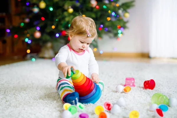 사랑스럽고 귀여운 작은 여아가 집이나 보육원에서 교육용 장난감을 가지고 놀고 있다. 건강하고 건강 한 아이가 화려 한 나무 소년 장난감 피라미드를 가지고 놀고 있습니다. 다른 기술을 배우는 아이. — 스톡 사진