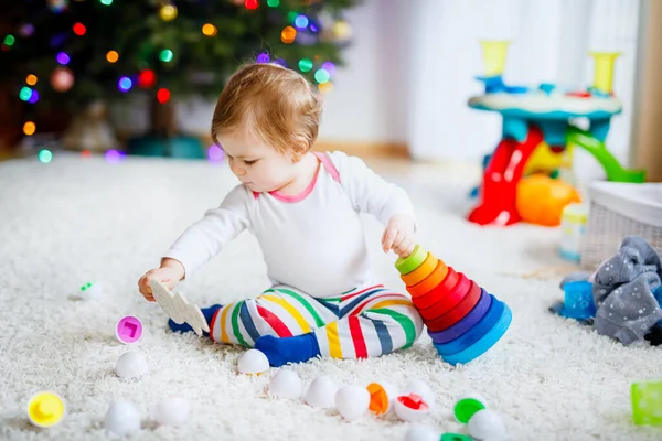 Adorable cute beautiful little baby girl playing with educational toys at home or nursery. Happy healthy child having fun with colorful wooden rainboy toy pyramid. Kid learning different skills. — Stock Photo, Image