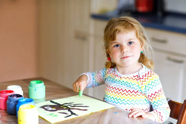 Little creative toddler girl painting with finger colors an owl bird. Active child having fun with drawing at home, in kindergaten or preschool. Games, education and distance learning for kids — Stock Photo, Image