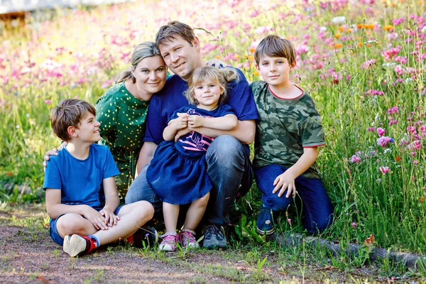 Sommarporträtt av föräldrar med tre barn. Mor, far, två barn bröder pojkar och liten söt småbarn syster flicka har kul tillsammans på blomsteräng. Lycklig familj på fem — Stockfoto