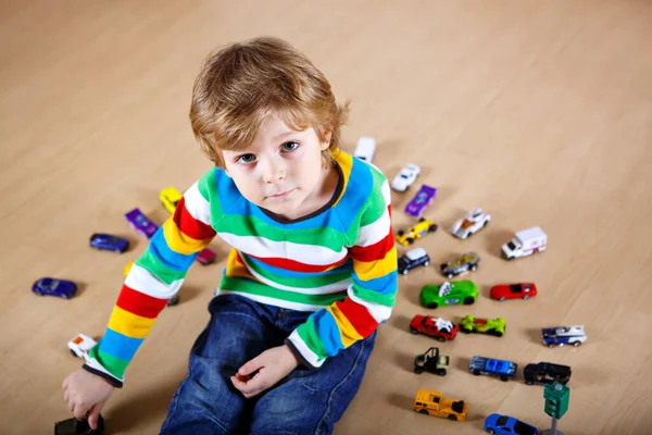 Uroczy blondyn bawiący się w domach zabawkami. Szczęśliwy zdrowy chłopiec bawiący się podczas pandemii choroby kwarantanny koronawirusowej. Dziecko samotnie w domu, zamknięty żłobek. — Zdjęcie stockowe