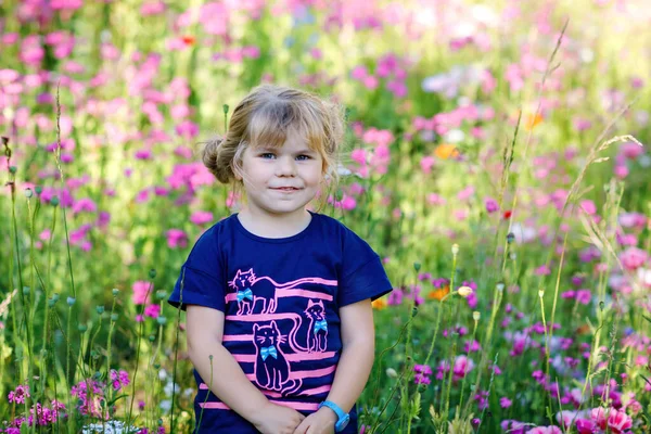 Portriat de adorable, encantadora niña en el prado de flores. Sonriente bebé feliz en el día de verano con flores de colores, al aire libre. Felicidad y verano. — Foto de Stock