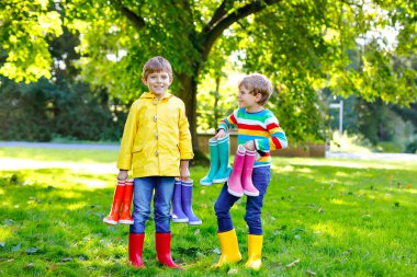 İki küçük çocuk, bir sürü renkli çizmeli şirin kardeşler. Farklı lastik botlar ve ceketler giymiş çocuklar. Yağmurlu bir sonbahar için ayakkabılar. Sağlıklı ikizler ve en iyi arkadaşlar dışarıda eğleniyorlar.