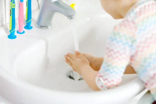 Close-up van kleine peuter meisje wassen handen met zeep en water in de badkamer. Close-up kind leren schoonmaken lichaamsdelen. Hygiëne routine actie tijdens virale desease. kind thuis of in de kinderkamer. — Stockfoto