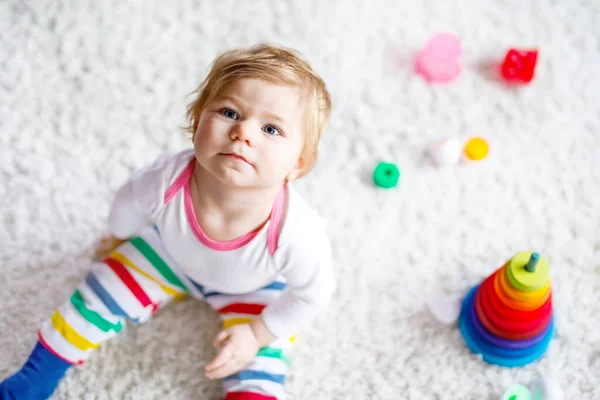 Adorable cute beautiful little baby girl playing with educational toys at home or nursery. Happy healthy child having fun with colorful wooden rainboy toy pyramid. Kid learning different skills. — Stock Photo, Image